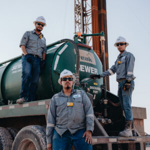 three workers posing with sewer trailer
